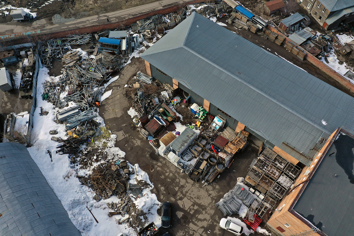 Aerial view of the Department of Road Management and Urban Improvement of the Tomsk city administration, including its storage facilities and operational base. This is the location where, according to official statements, the dismantled Stone of Sorrow memorial was relocated.